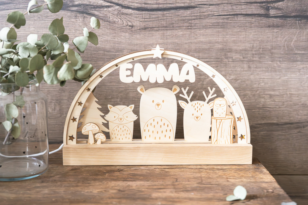 LED-Schwibbogen aus Holz mit gravierter Waldtier-Szene (Fuchs, Bär, Reh, Eule) und dem Namen „Emma" in Druckbuchstaben, umrahmt von Sternen, warmweißes Licht